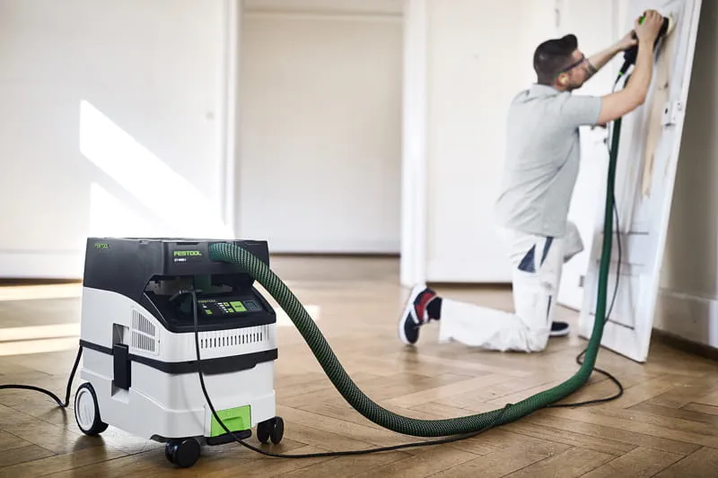 Worker sanding and using dust extractor