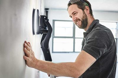 A man uses the Planex with lighting to sand a wall