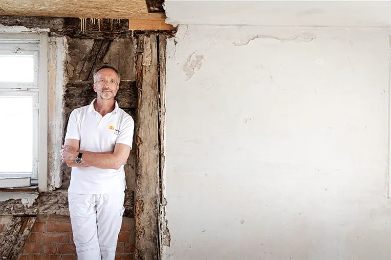 Manfred Schuler, master painter and restorer, in front of the wall in the timber frame house to be restored